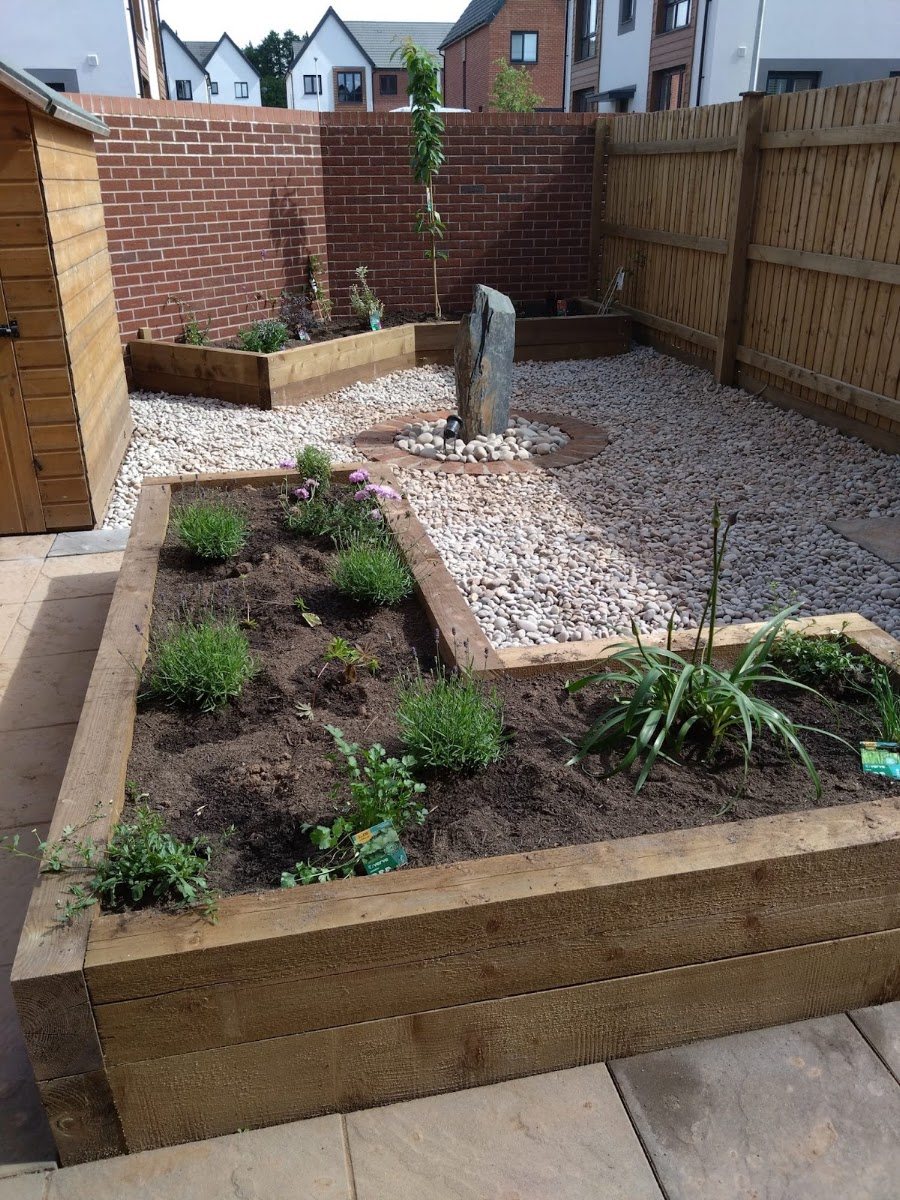 Raised sleeper beds with gravel path and planting